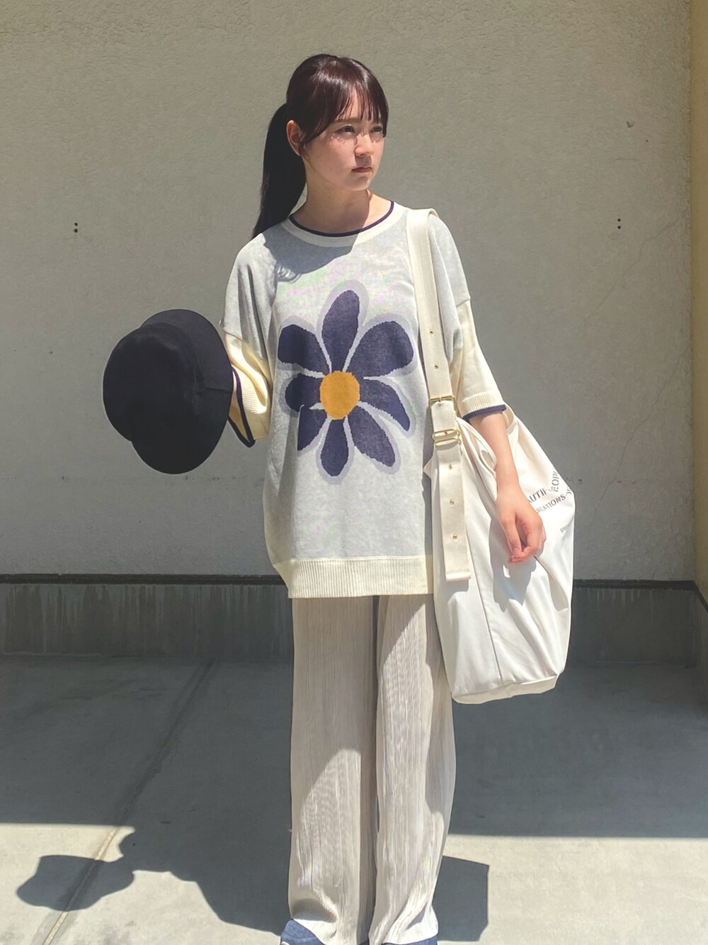 ホワイト系のニット/セーター、ホワイト系のトートバッグ、ホワイト系のその他パンツを着用したレディースの夏コーディネートの2枚目の写真