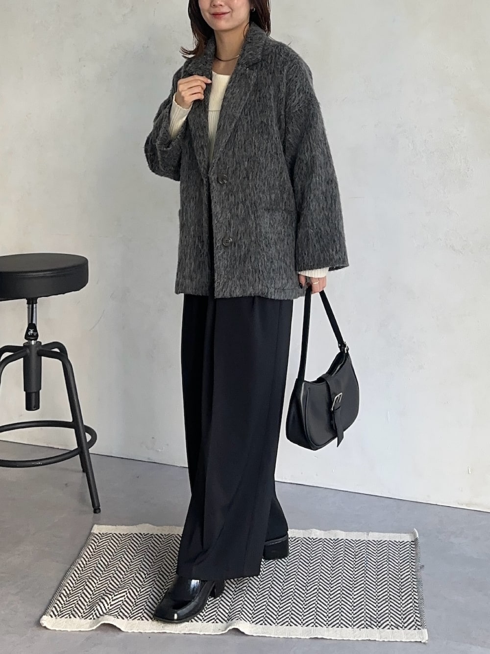 ホワイト系のニット/セーター、ブラック系のスラックス、グレー系のその他アウターを着用したレディースの冬コーディネートの6枚目の写真