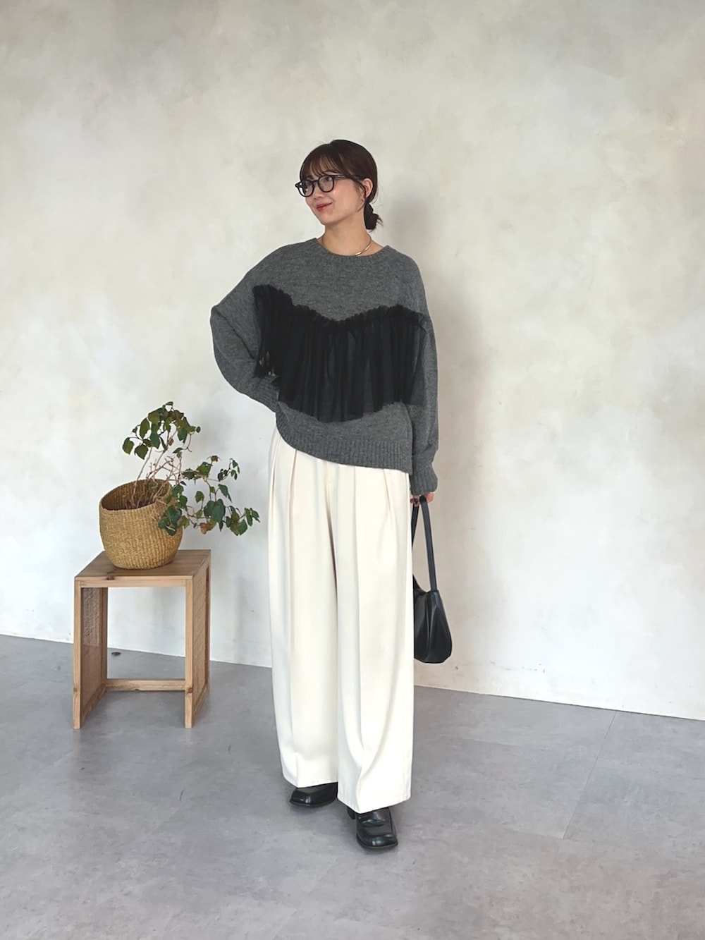 グレー系のニット/セーター、ホワイト系のスラックス、ブラック系のベルトを着用したレディースの冬コーディネートの2枚目の写真