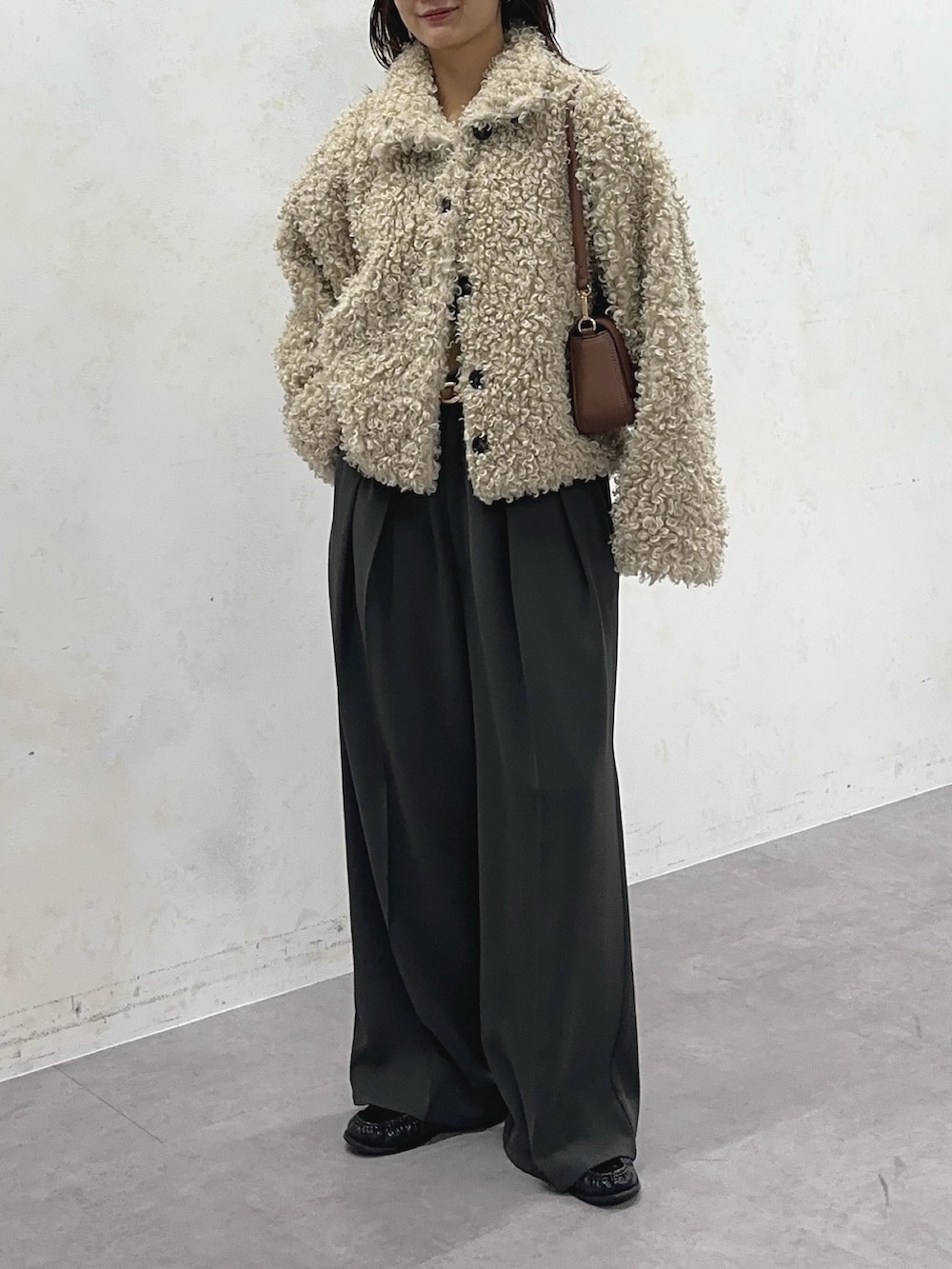 ホワイト系のブルゾン、グレー系のスラックス、ベージュ系のベルトを着用したレディースの冬コーディネートの3枚目の写真