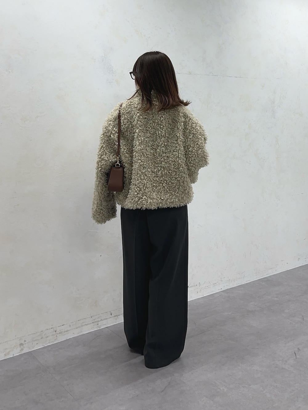 ホワイト系のブルゾン、グレー系のスラックス、ベージュ系のベルトを着用したレディースの冬コーディネートの2枚目の写真