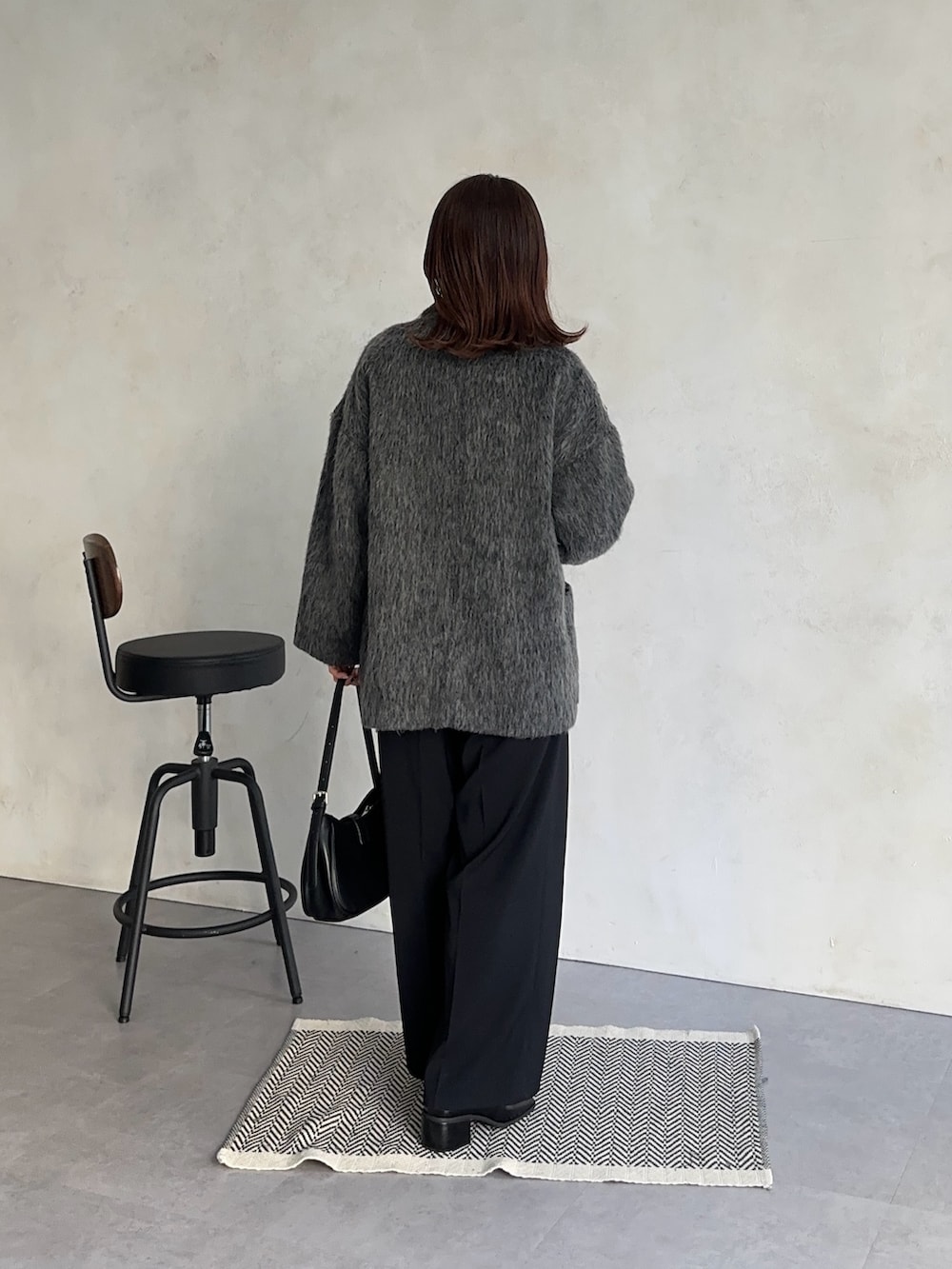 ホワイト系のニット/セーター、ブラック系のスラックス、グレー系のその他アウターを着用したレディースの冬コーディネートの5枚目の写真