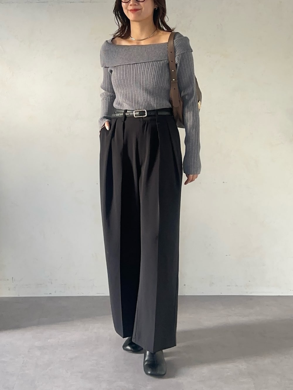 ブラック系のスラックス、グレー系のニット/セーター、ブラック系のベルトを着用したレディースの秋コーディネートの2枚目の写真