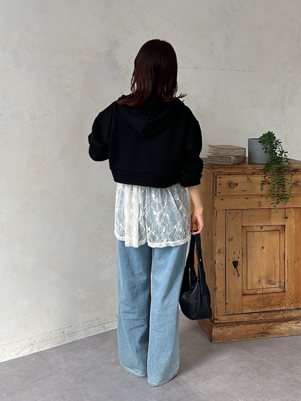 ブラック系のパーカー、ホワイト系のチュニック、ブルー系のその他パンツを着用したレディースの冬コーディネートの4枚目の写真