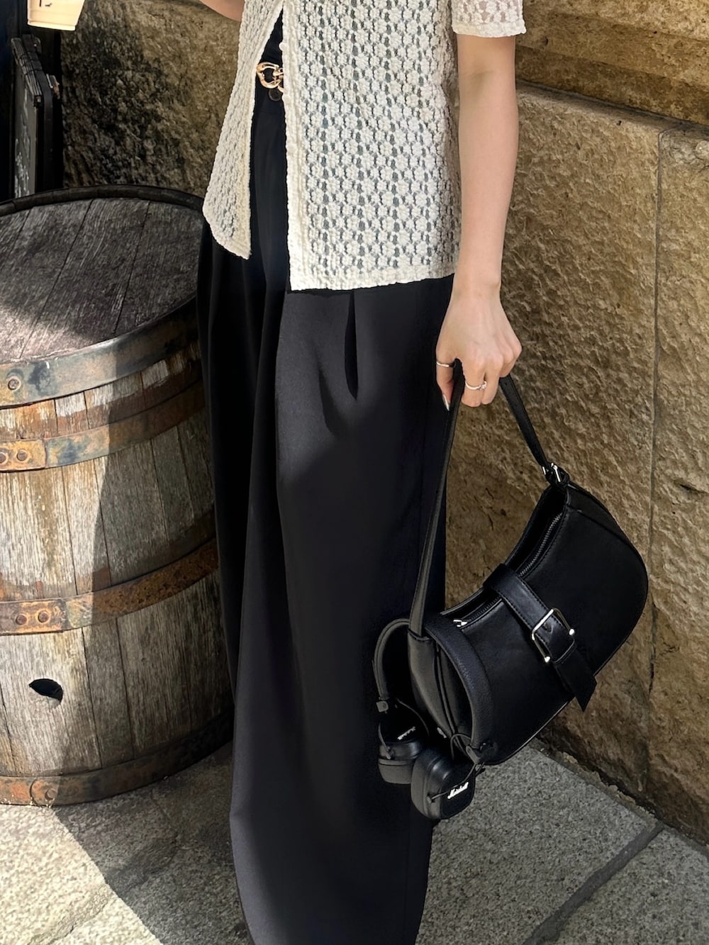 ブラック系のスラックス、ブラック系のボストンバッグ、ブラック系のベルトを着用したレディースの夏コーディネートの2枚目の写真