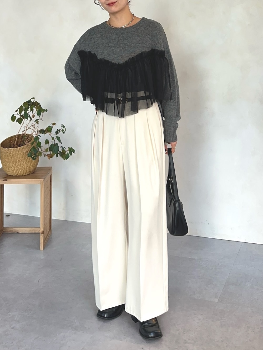 グレー系のニット/セーター、ホワイト系のスラックス、ブラック系のベルトを着用したレディースの冬コーディネートの3枚目の写真