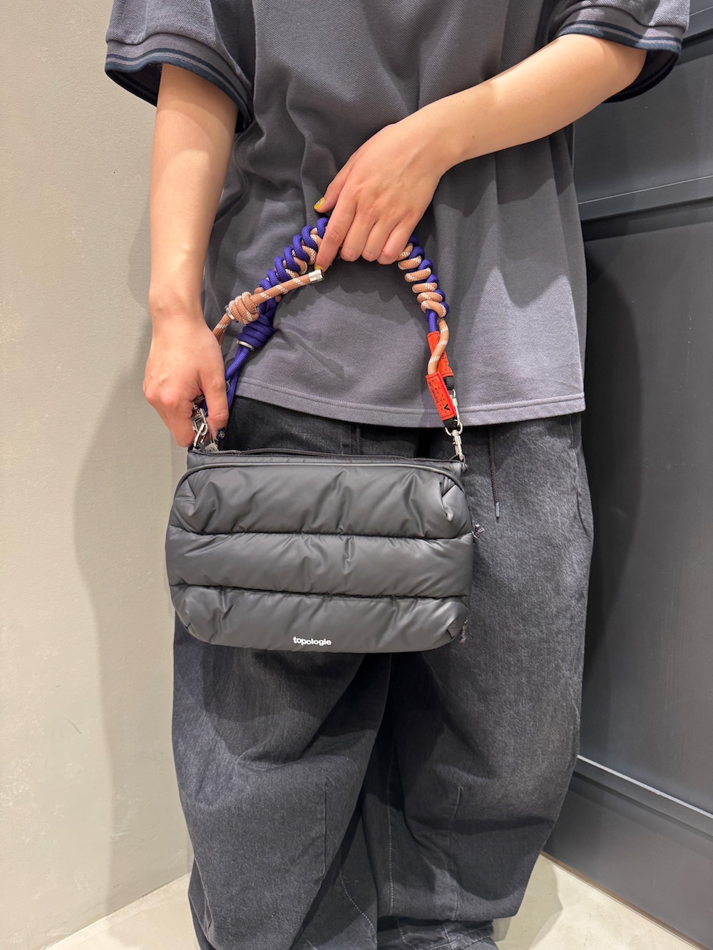 ブラック系のショルダーバッグ、ブラック系のスニーカー、パープル系のスマホグッズを着用したレディースの夏コーディネートの4枚目の写真