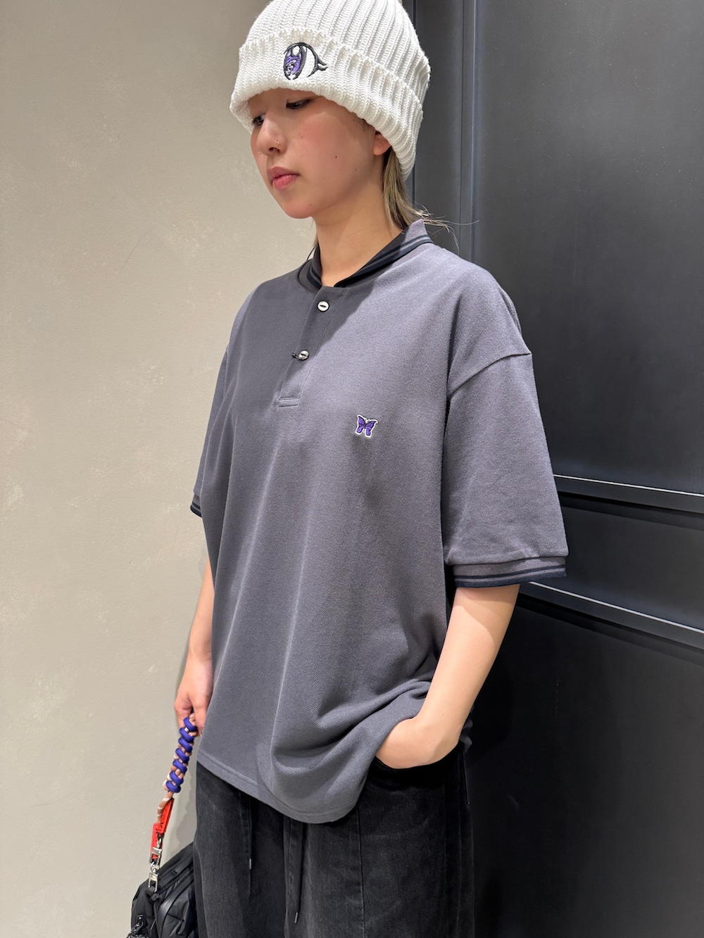 ブラック系のショルダーバッグ、ブラック系のスニーカー、パープル系のスマホグッズを着用したレディースの夏コーディネートの2枚目の写真