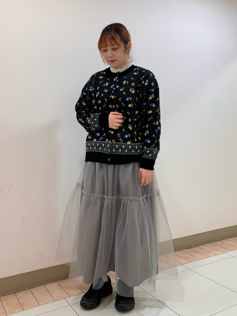 ブラック系のカーディガン/ボレロ、ホワイト系のニット/セーター、グレー系のスカートを着用したレディースの冬コーディネートの2枚目の写真