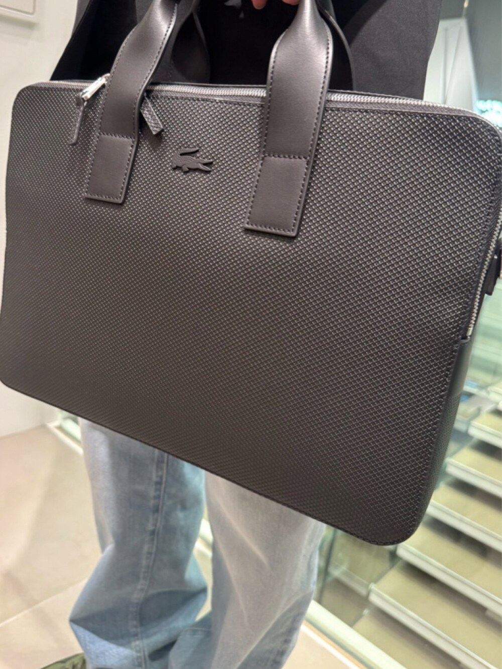 ブラック系のテーラードジャケット、グレー系のニット/セーター、ブルー系のデニムパンツを着用したメンズの春コーディネートの4枚目の写真