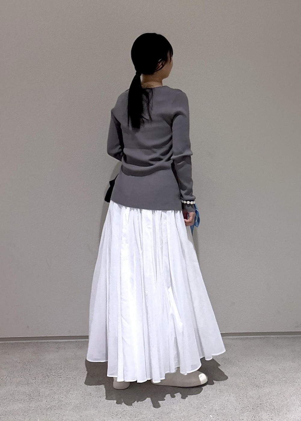 ブルー系のハンドバッグ、グレー系のカーディガン/ボレロ、ホワイト系のスカートを着用したレディースの冬コーディネートの6枚目の写真