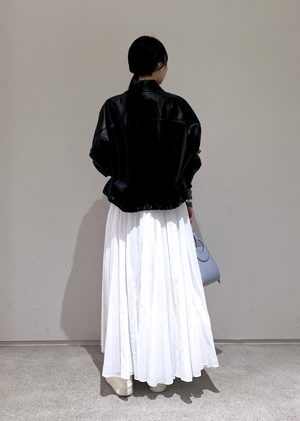 ブルー系のハンドバッグ、グレー系のカーディガン/ボレロ、ホワイト系のスカートを着用したレディースの冬コーディネートの3枚目の写真