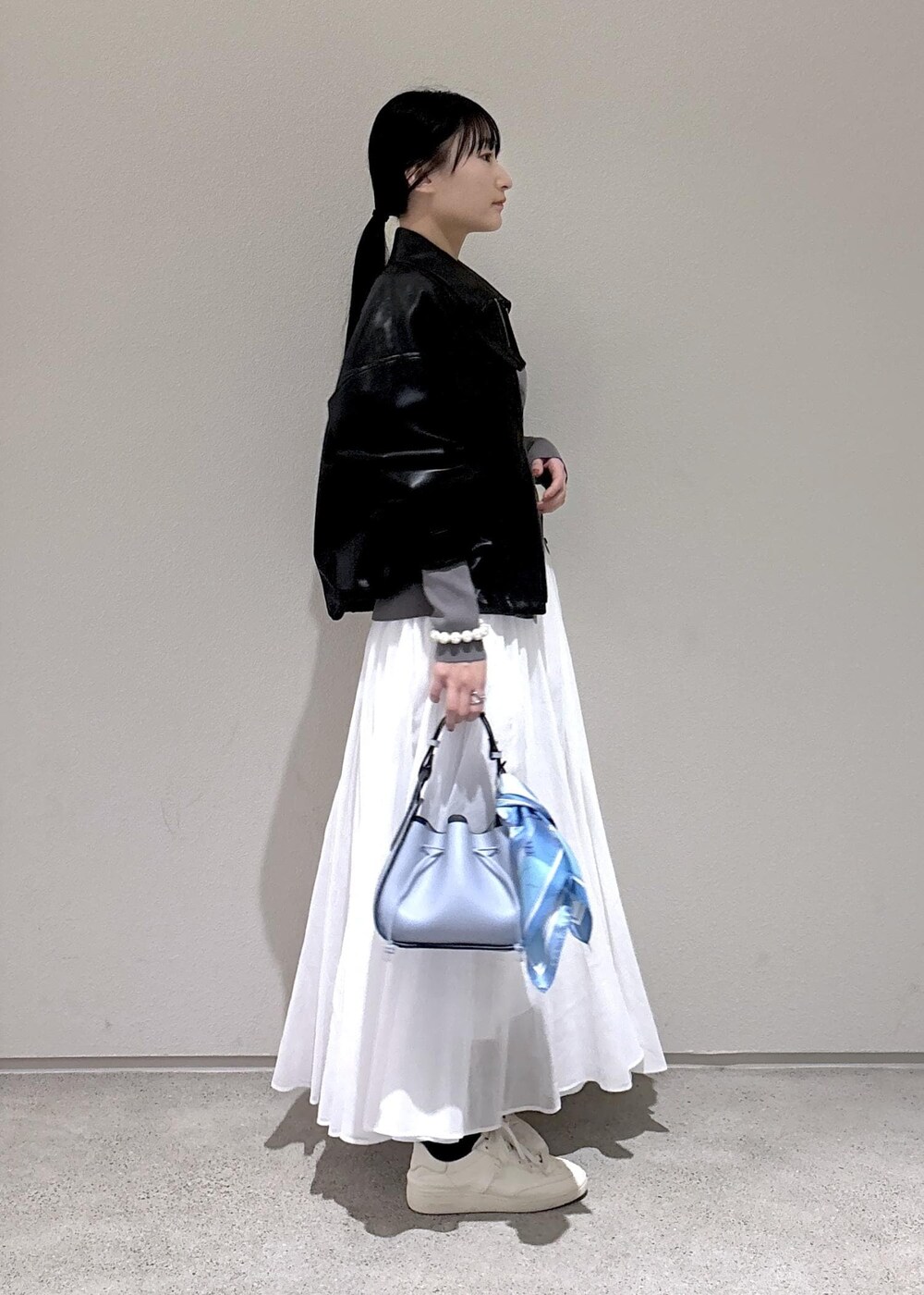 ブルー系のハンドバッグ、グレー系のカーディガン/ボレロ、ホワイト系のスカートを着用したレディースの冬コーディネートの2枚目の写真