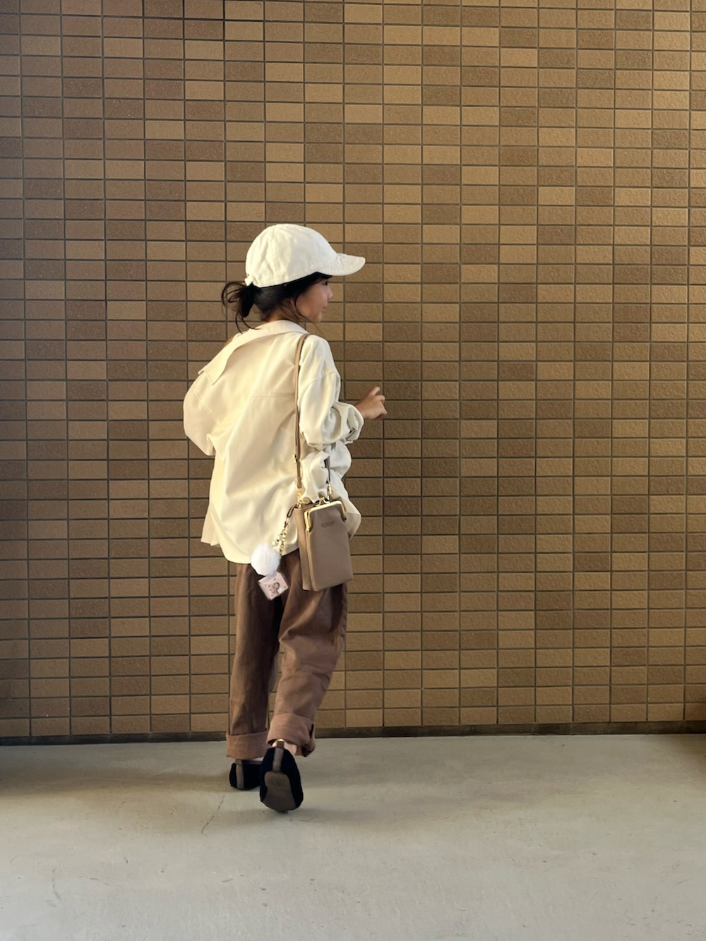 ブラウン系のデニムパンツ、ベージュ系のパンプスを着用したキッズの秋コーディネートの2枚目の写真