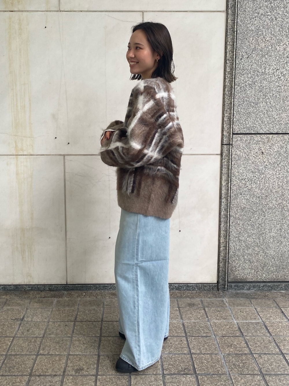 ホワイト系のTシャツ/カットソー、ブルー系のデニムパンツ、ブラウン系のニット/セーターを着用したレディースの秋コーディネートの2枚目の写真