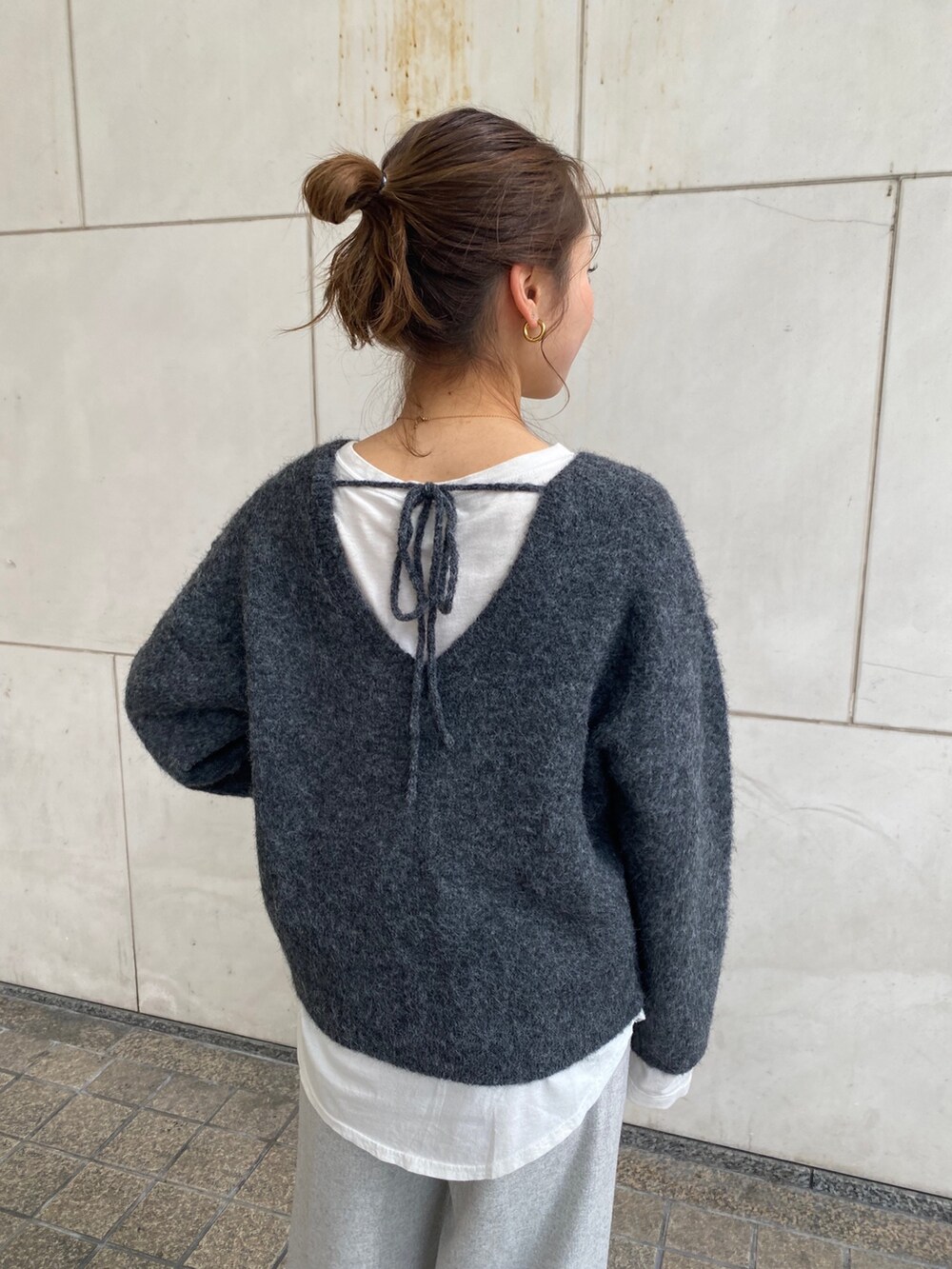 グレー系のニット/セーター、ホワイト系のTシャツ/カットソー、グレー系のその他パンツを着用したレディースの冬コーディネートの4枚目の写真