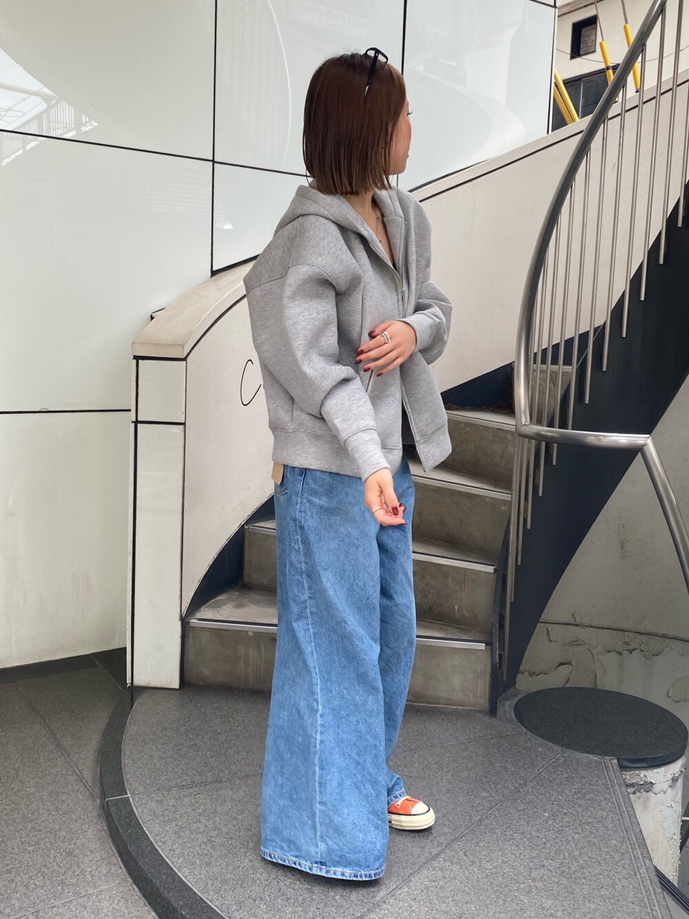 ブルー系のデニムパンツ、グレー系のパーカー、シルバー系のネックレスを着用したレディースの秋コーディネートの2枚目の写真