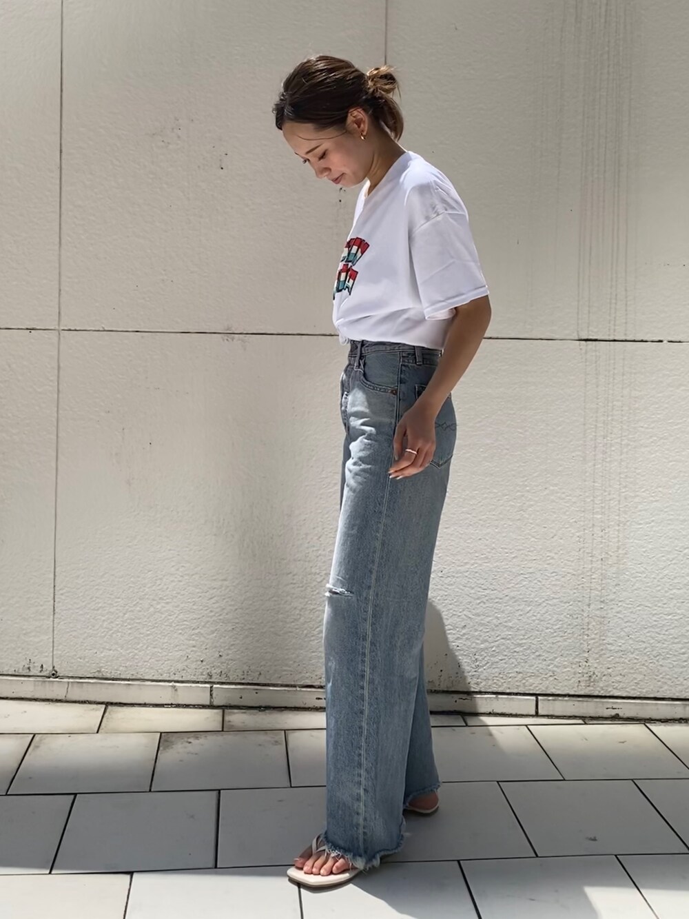 ブルー系のデニムパンツ、ホワイト系のサンダル、ホワイト系のTシャツ/カットソーを着用したレディースの夏コーディネートの3枚目の写真