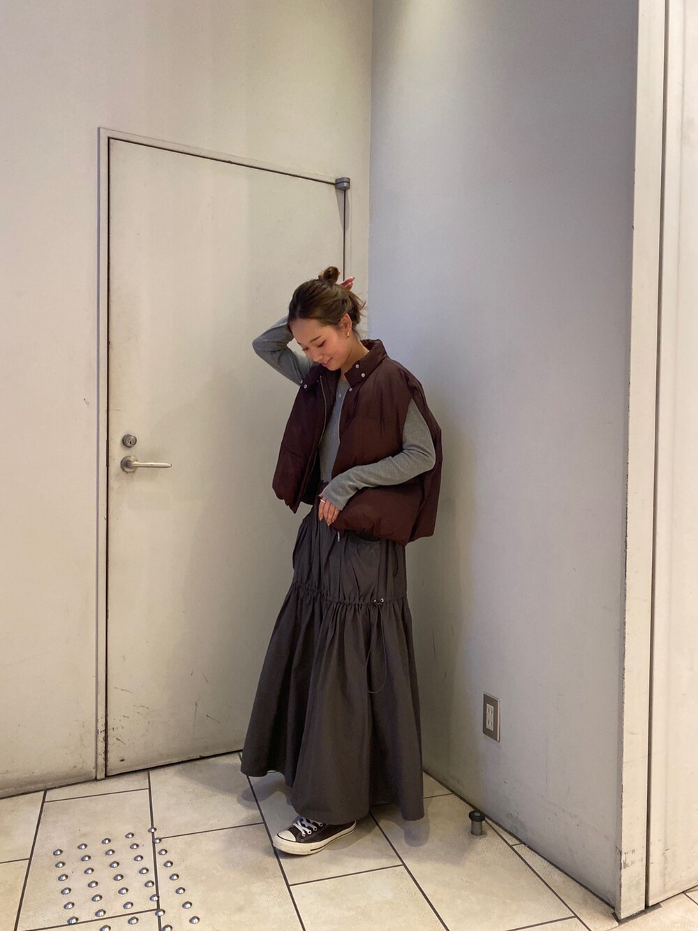 グレー系のワンピース、ブラウン系のダウンベストを着用したレディースの秋コーディネートの3枚目の写真
