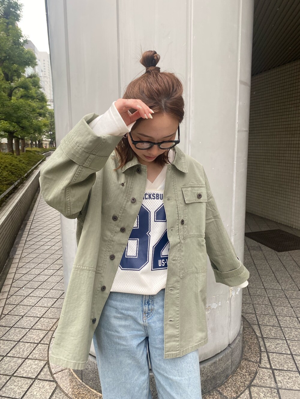 ブルー系のデニムパンツ、グリーン系のミリタリージャケット、ホワイト系のTシャツ/カットソーを着用したレディースの春コーディネートの4枚目の写真