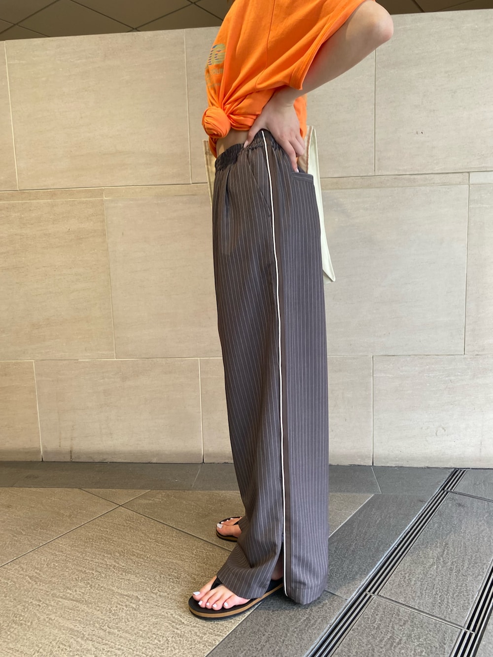 グレー系のその他パンツ、オレンジ系のTシャツ/カットソー、ホワイト系のトートバッグを着用したレディースの夏コーディネートの5枚目の写真