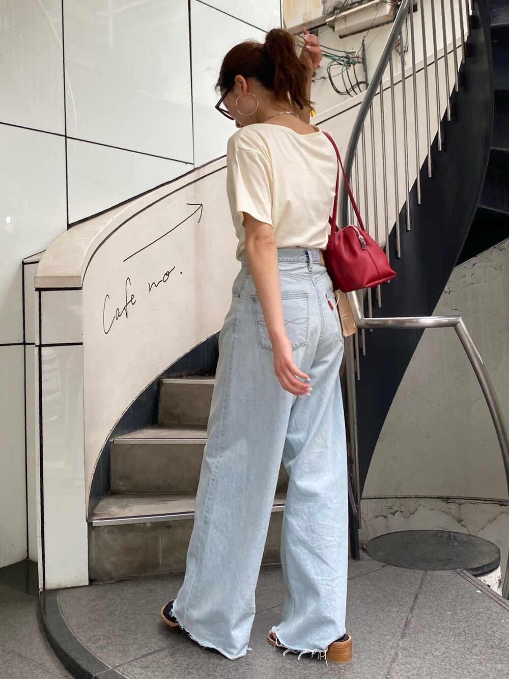 ブルー系のデニムパンツ、ブラック系のサンダル、ホワイト系のTシャツ/カットソーを着用したレディースの夏コーディネートの3枚目の写真