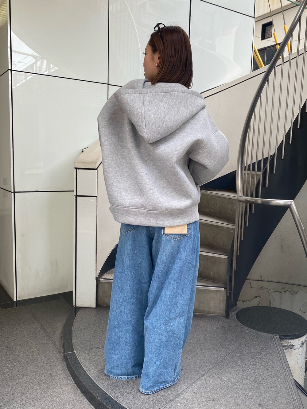 ブルー系のデニムパンツ、グレー系のパーカー、シルバー系のネックレスを着用したレディースの秋コーディネートの3枚目の写真