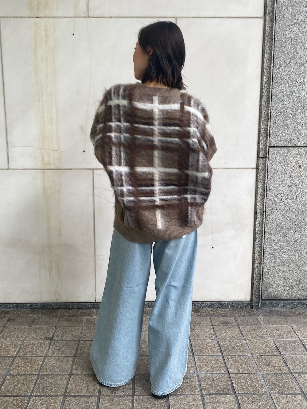 ホワイト系のTシャツ/カットソー、ブルー系のデニムパンツ、ブラウン系のニット/セーターを着用したレディースの秋コーディネートの3枚目の写真