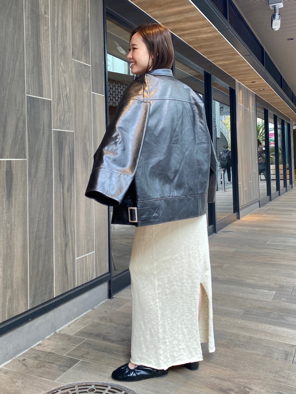 ホワイト系のスカート、ブラック系のブルゾン、グレー系のTシャツ/カットソーを着用したレディースの冬コーディネートの3枚目の写真