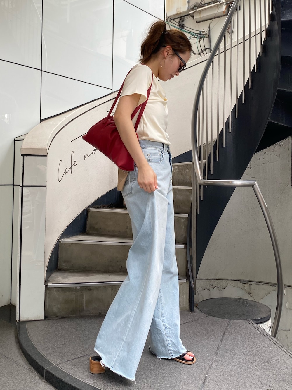 ブルー系のデニムパンツ、ブラック系のサンダル、ホワイト系のTシャツ/カットソーを着用したレディースの夏コーディネートの2枚目の写真