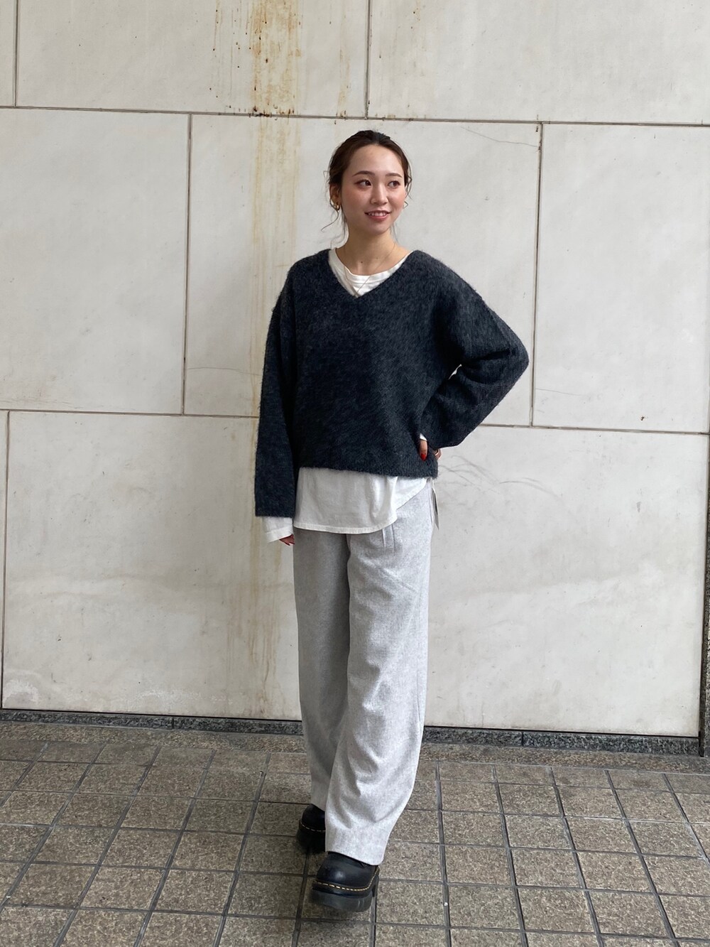 グレー系のニット/セーター、ホワイト系のTシャツ/カットソー、グレー系のその他パンツを着用したレディースの冬コーディネートの2枚目の写真