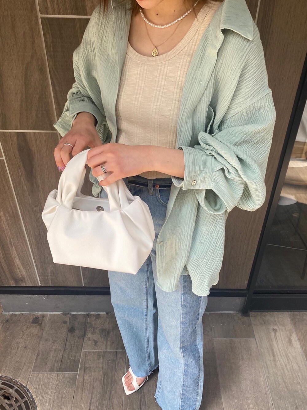 グリーン系のシャツ/ブラウス、ブルー系のデニムパンツ、ホワイト系のハンドバッグを着用したレディースの春コーディネートの3枚目の写真