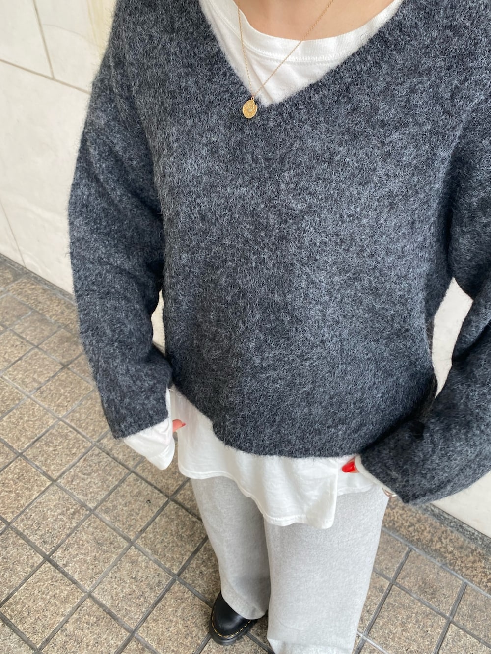 グレー系のニット/セーター、ホワイト系のTシャツ/カットソー、グレー系のその他パンツを着用したレディースの冬コーディネートの6枚目の写真