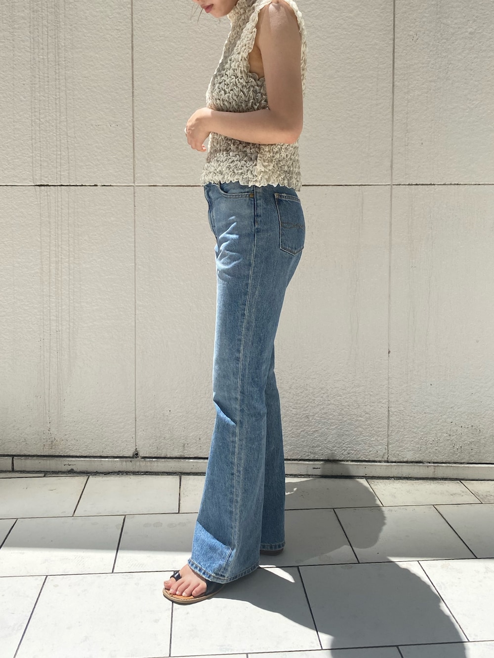 ブルー系のデニムパンツ、ホワイト系のシャツ/ブラウス、ブラック系のサンダルを着用したレディースの夏コーディネートの4枚目の写真