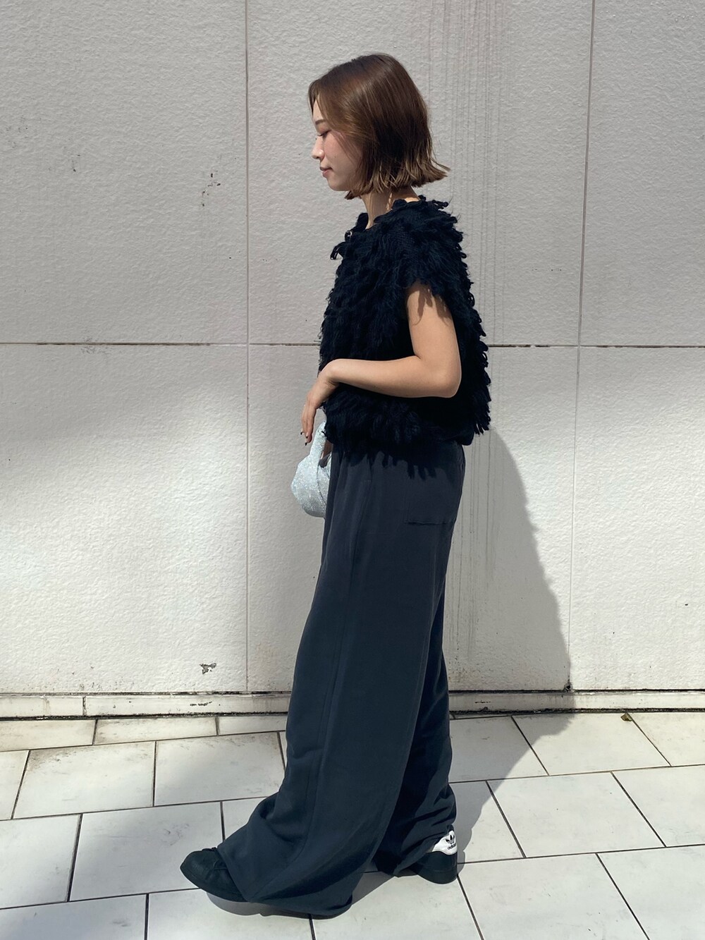 ブラック系のハンドバッグ、グレー系のスウェットパンツ、ブラック系のベストを着用したレディースの秋コーディネートの2枚目の写真