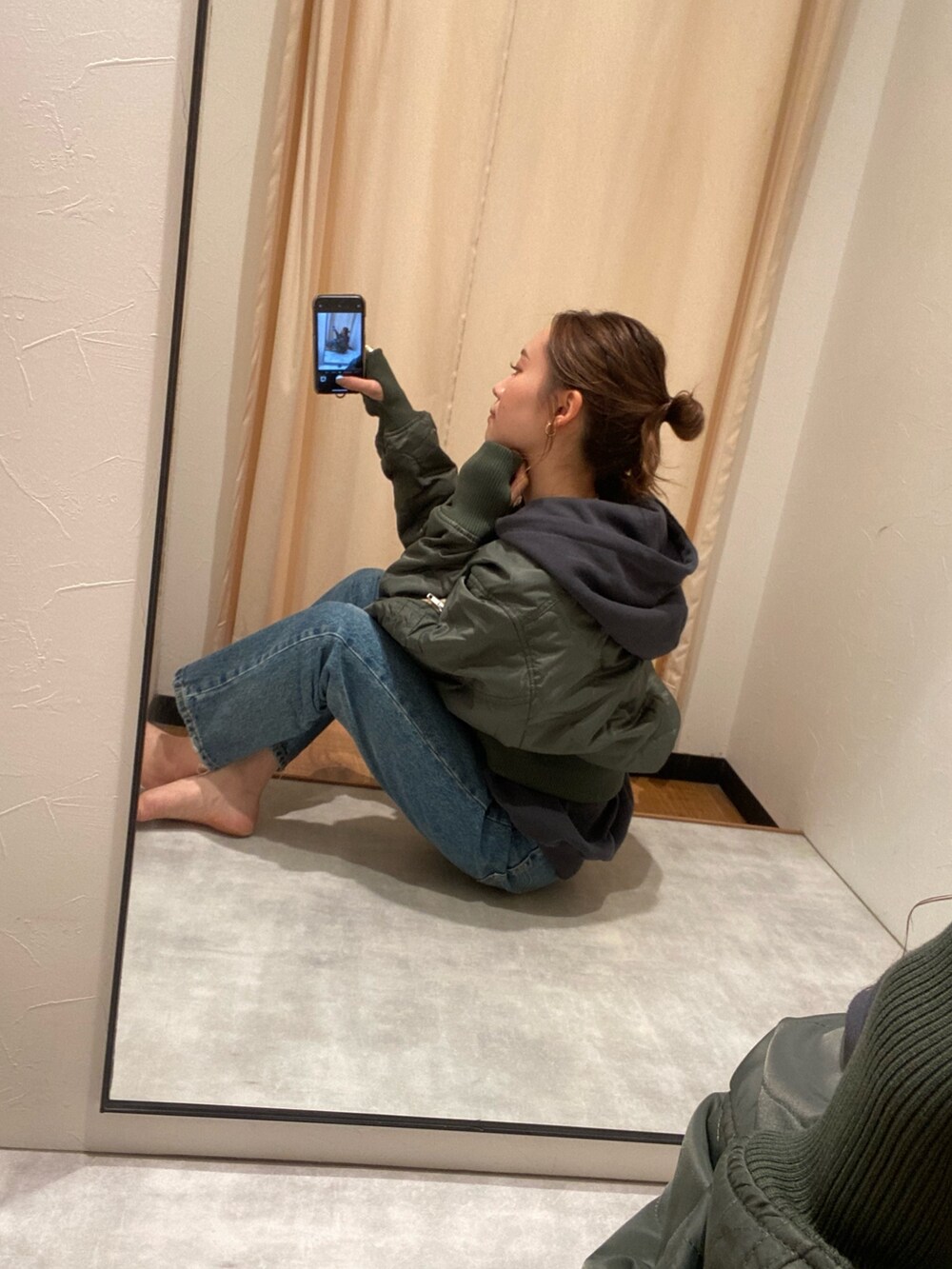 ベージュ系のブルゾン、グレー系のパーカー、ブルー系のデニムパンツを着用したレディースの秋コーディネートの2枚目の写真