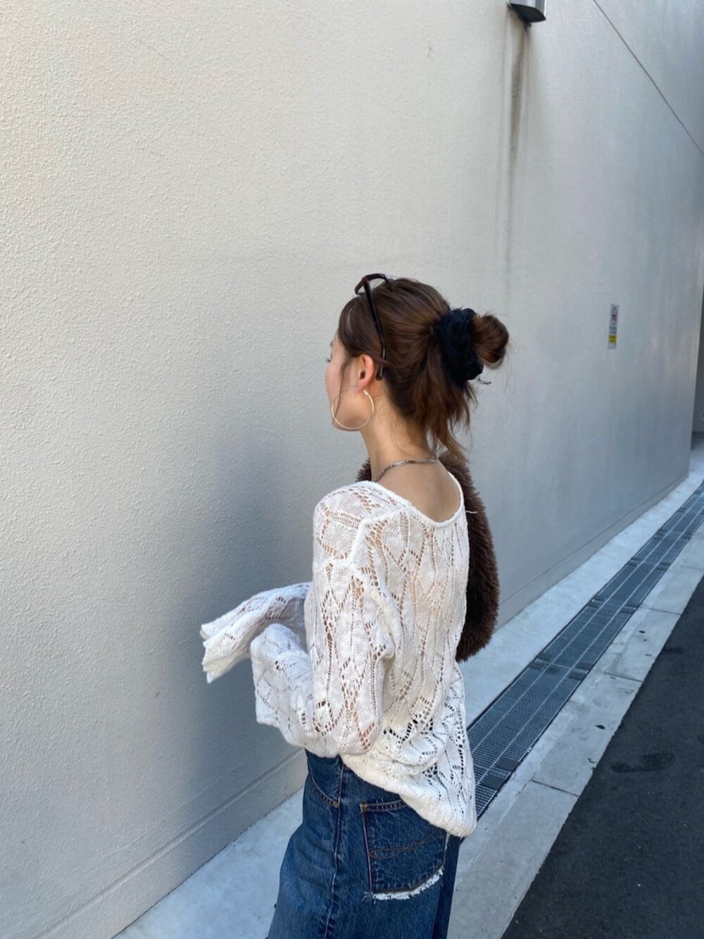 ブルー系のデニムパンツ、ホワイト系のニット/セーター、ブラウン系のハンドバッグを着用したレディースの夏コーディネートの4枚目の写真