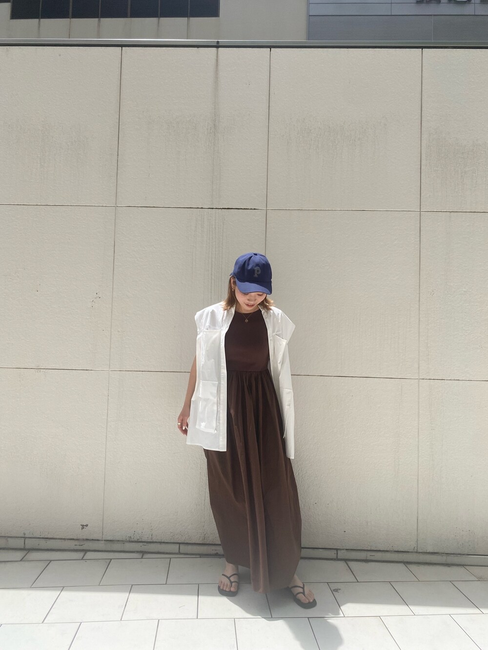 ブラウン系のワンピース、ブルー系のキャップを着用したレディースの夏コーディネートの2枚目の写真