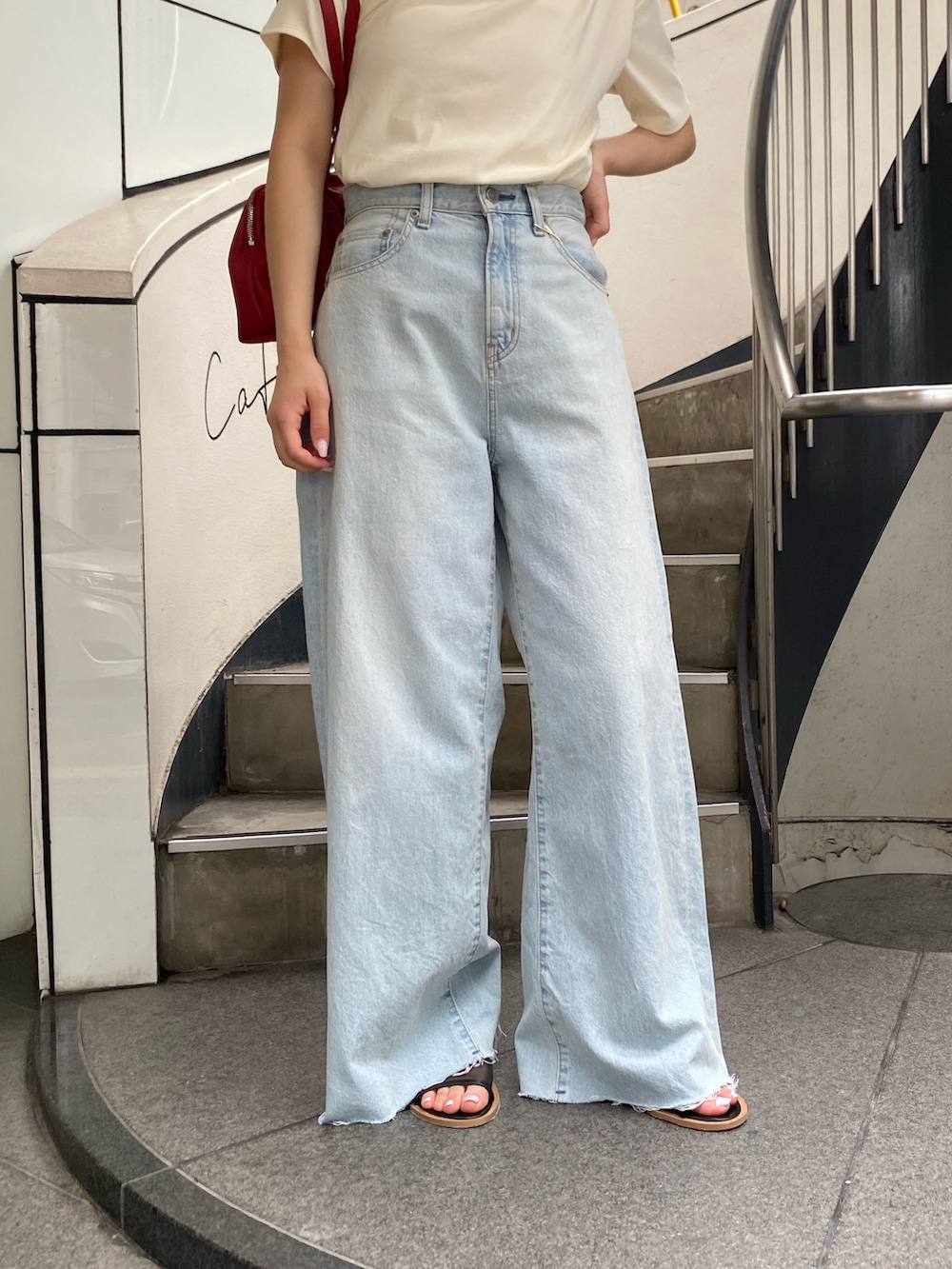 ブルー系のデニムパンツ、ブラック系のサンダル、ホワイト系のTシャツ/カットソーを着用したレディースの夏コーディネートの5枚目の写真