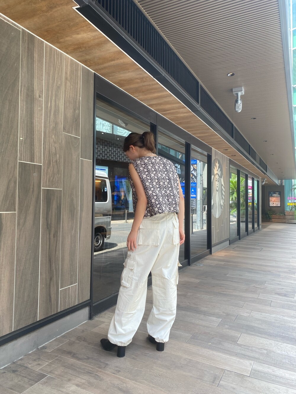 ホワイト系のカーゴパンツ、ブラック系のベスト、ホワイト系のキャミソールを着用したレディースの夏コーディネートの2枚目の写真