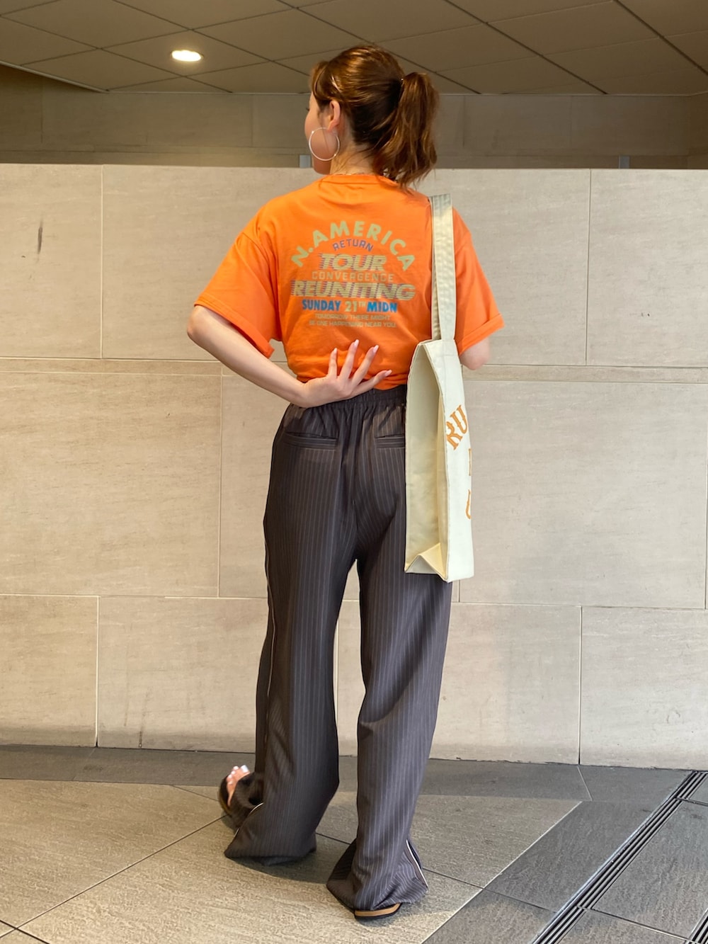 グレー系のその他パンツ、オレンジ系のTシャツ/カットソー、ホワイト系のトートバッグを着用したレディースの夏コーディネートの3枚目の写真