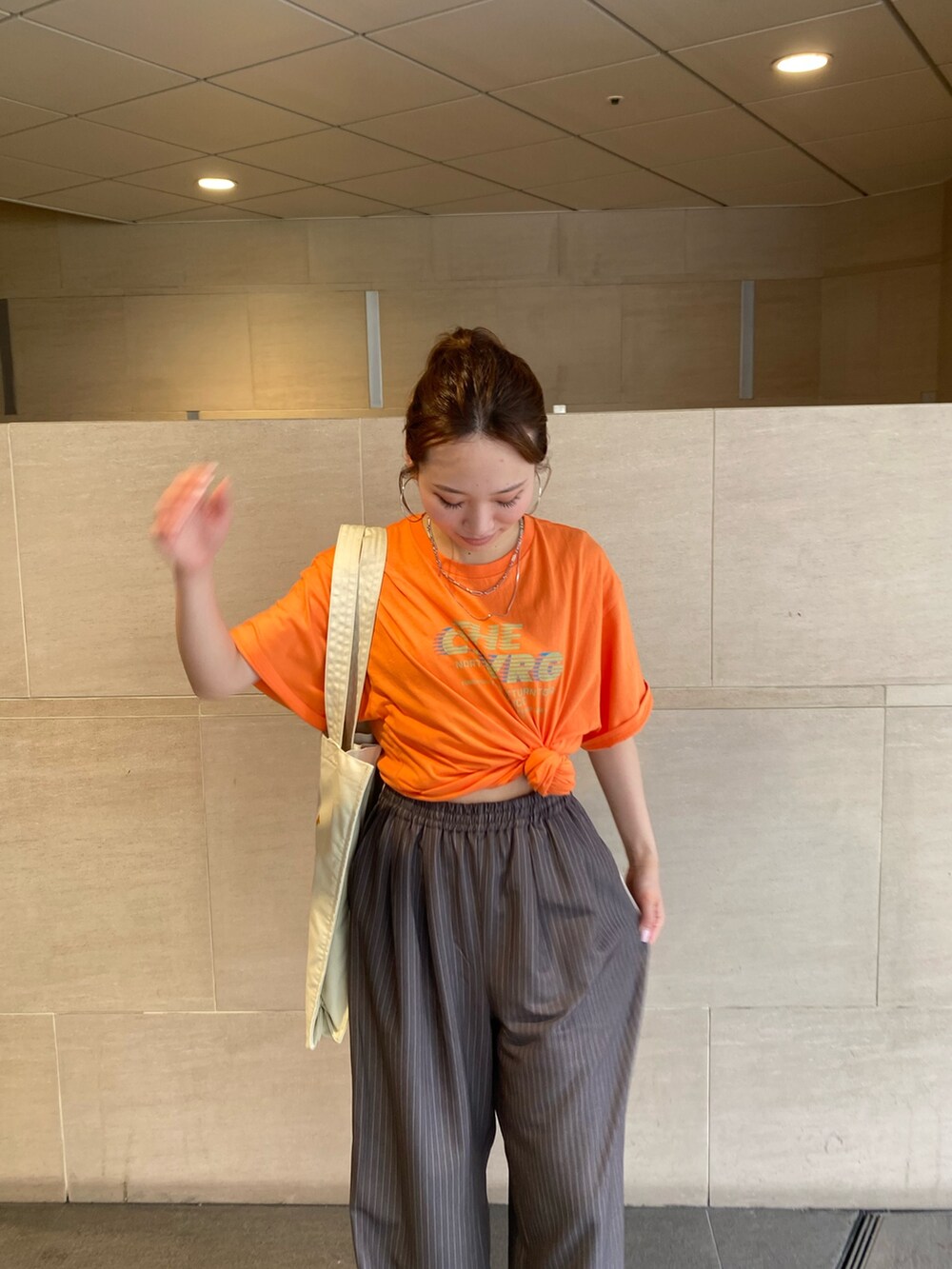 グレー系のその他パンツ、オレンジ系のTシャツ/カットソー、ホワイト系のトートバッグを着用したレディースの夏コーディネートの4枚目の写真