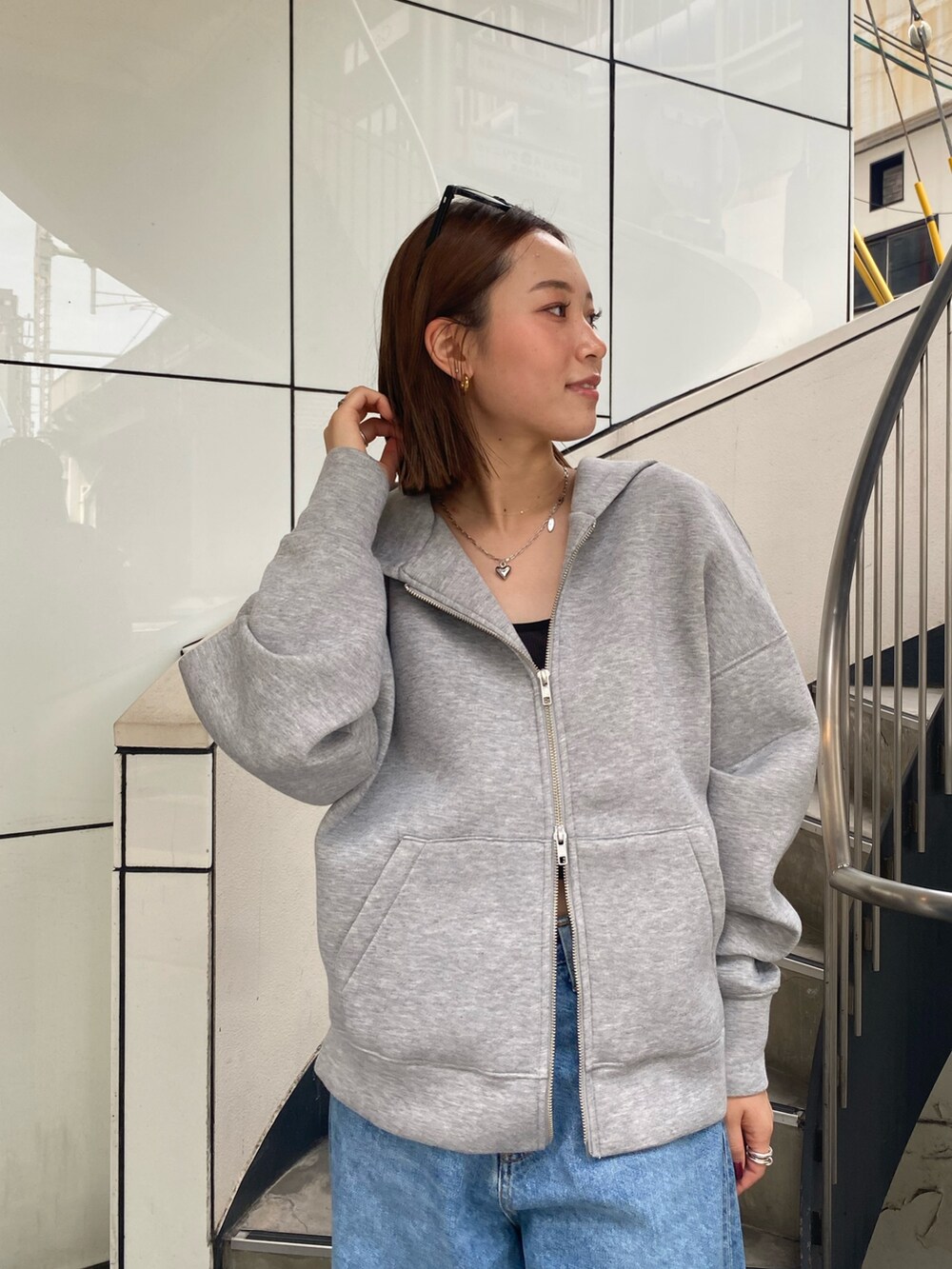 ブルー系のデニムパンツ、グレー系のパーカー、シルバー系のネックレスを着用したレディースの秋コーディネートの4枚目の写真