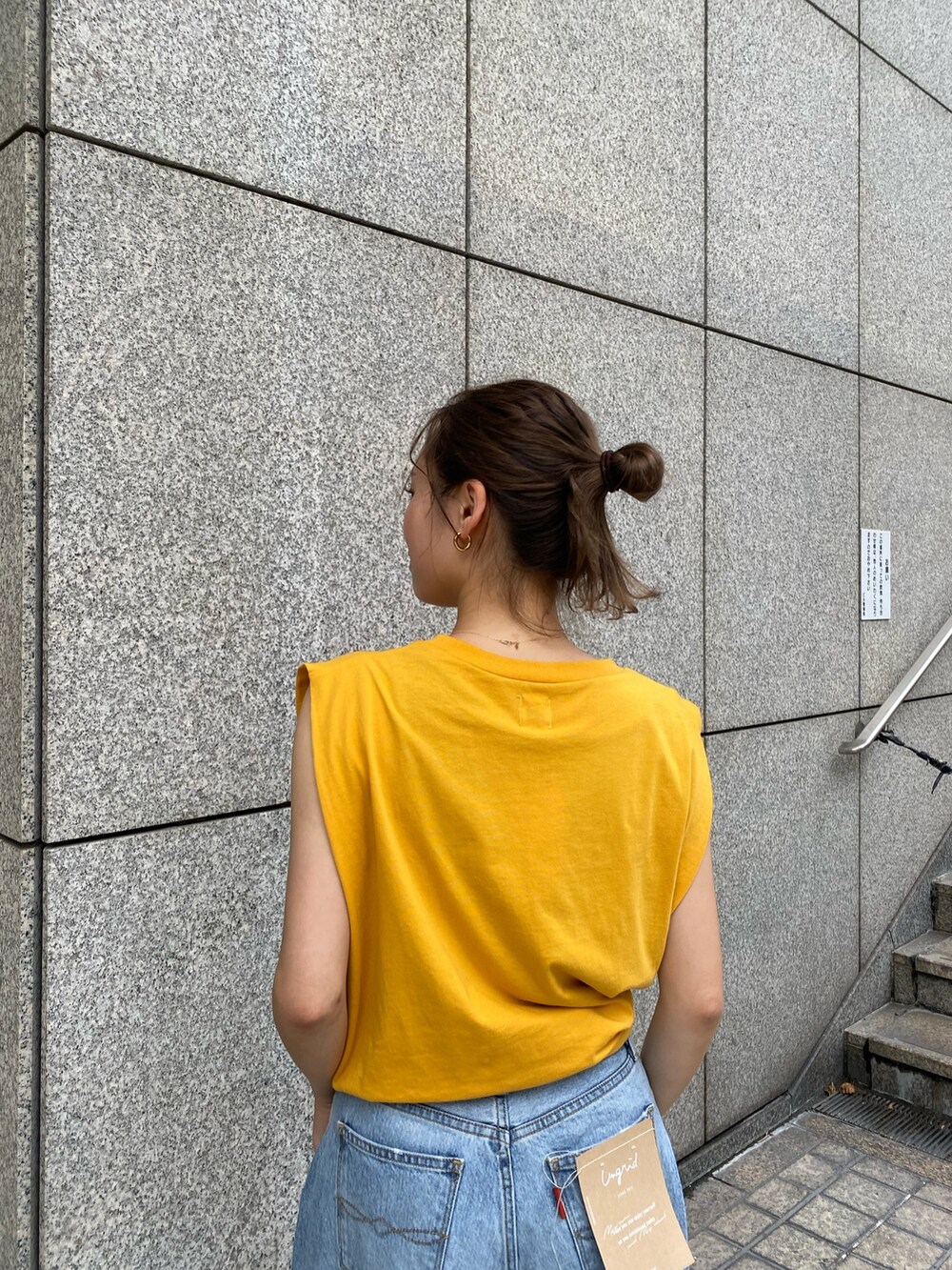 ブルー系のデニムパンツ、イエロー系のTシャツ/カットソー、ブラック系のサンダルを着用したレディースの夏コーディネートの4枚目の写真