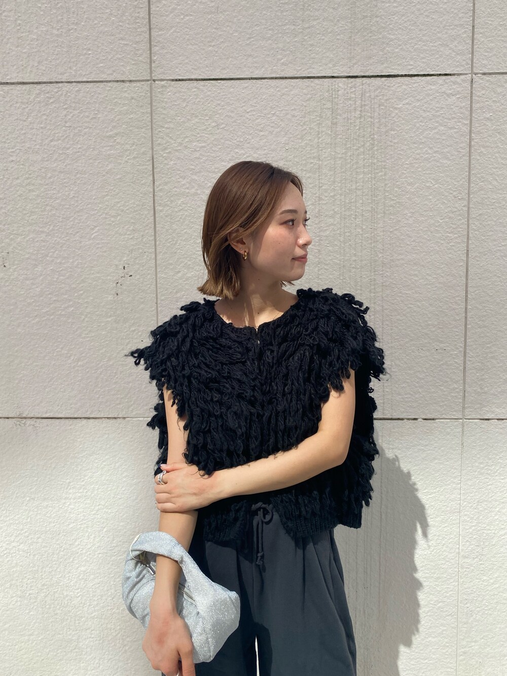 ブラック系のハンドバッグ、グレー系のスウェットパンツ、ブラック系のベストを着用したレディースの秋コーディネートの4枚目の写真