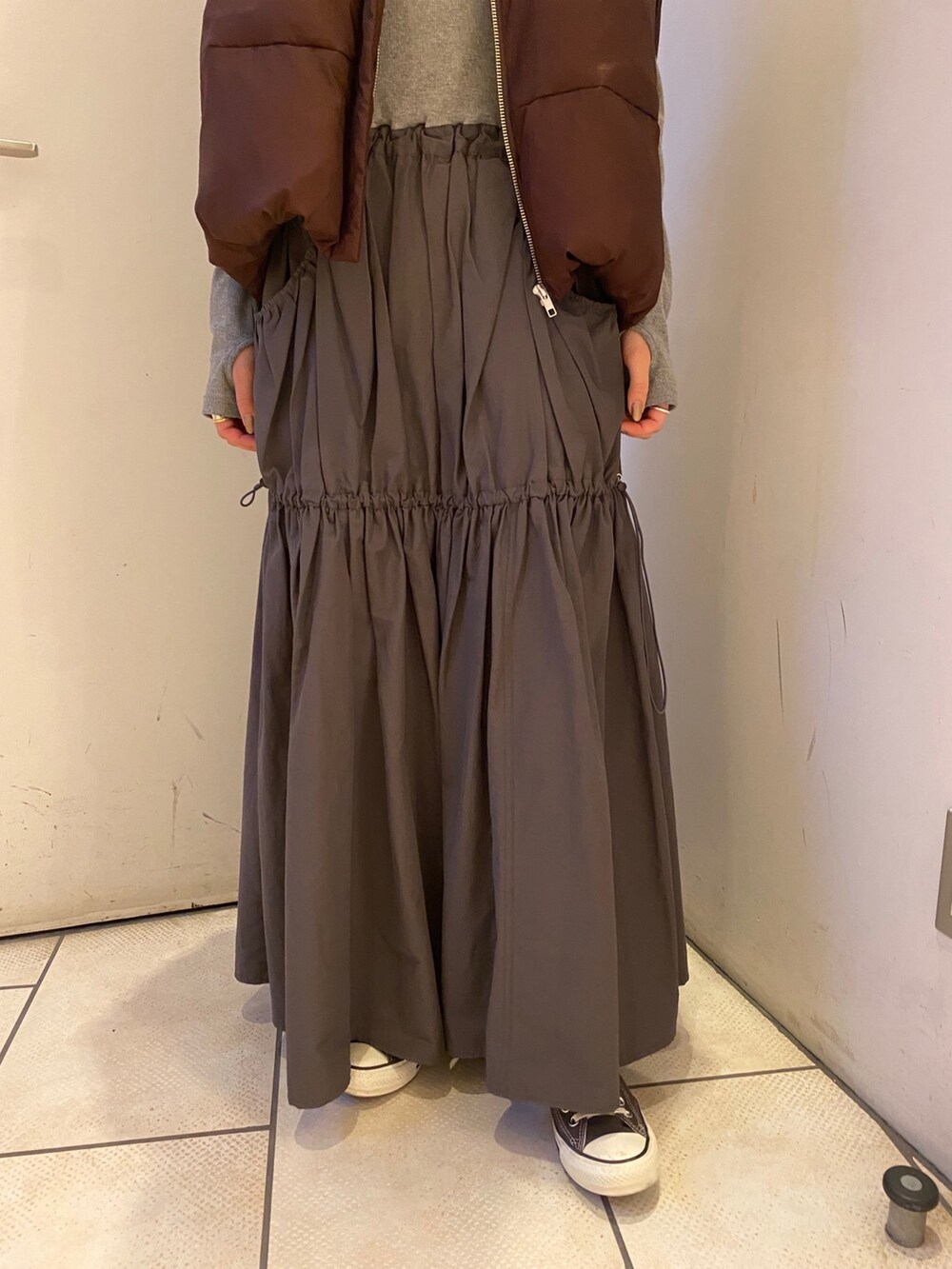 グレー系のワンピース、ブラウン系のダウンベストを着用したレディースの秋コーディネートの5枚目の写真