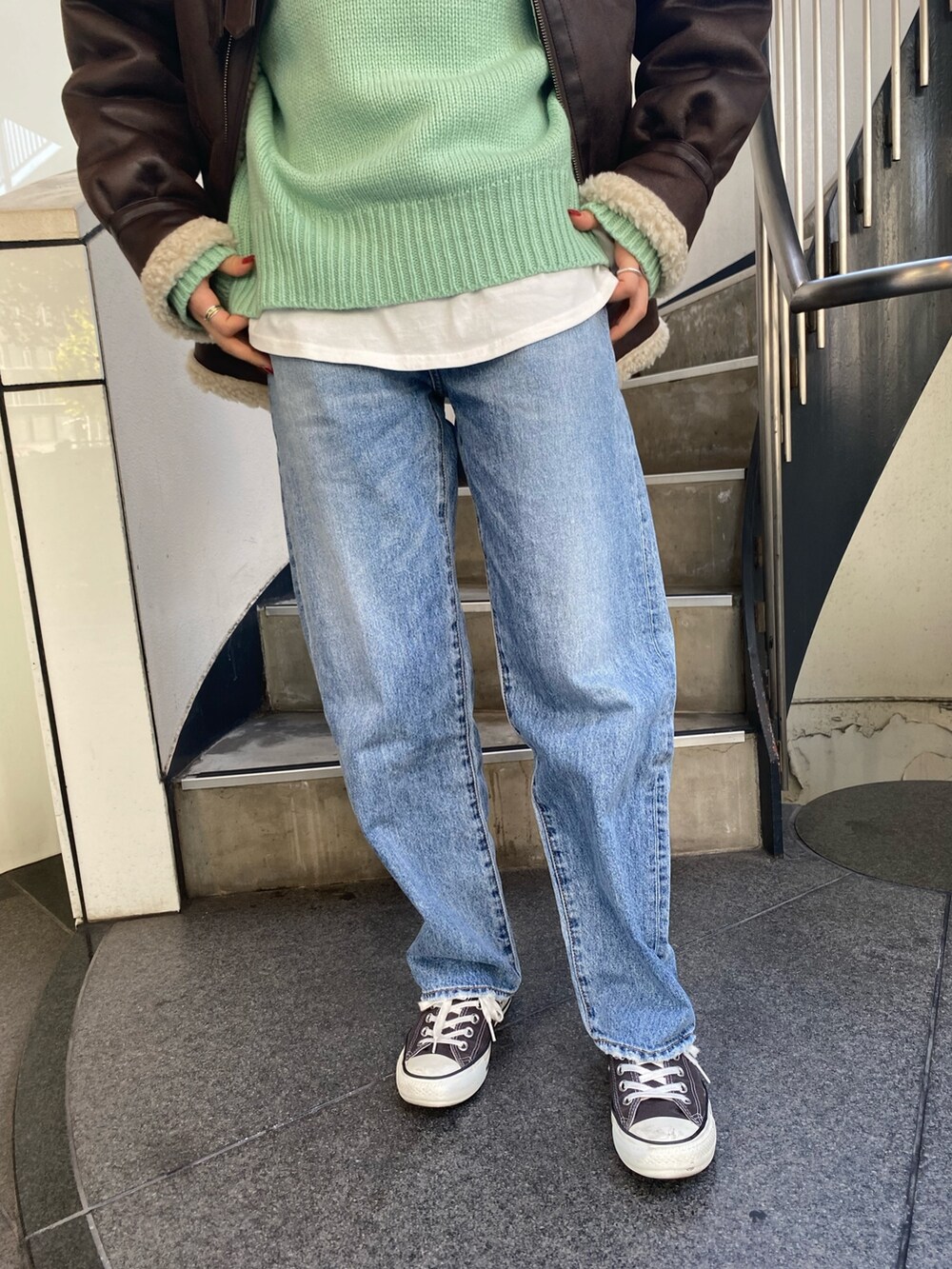 ブルー系のデニムパンツ、グリーン系のニット/セーター、ホワイト系のTシャツ/カットソーを着用したレディースの秋コーディネートの4枚目の写真