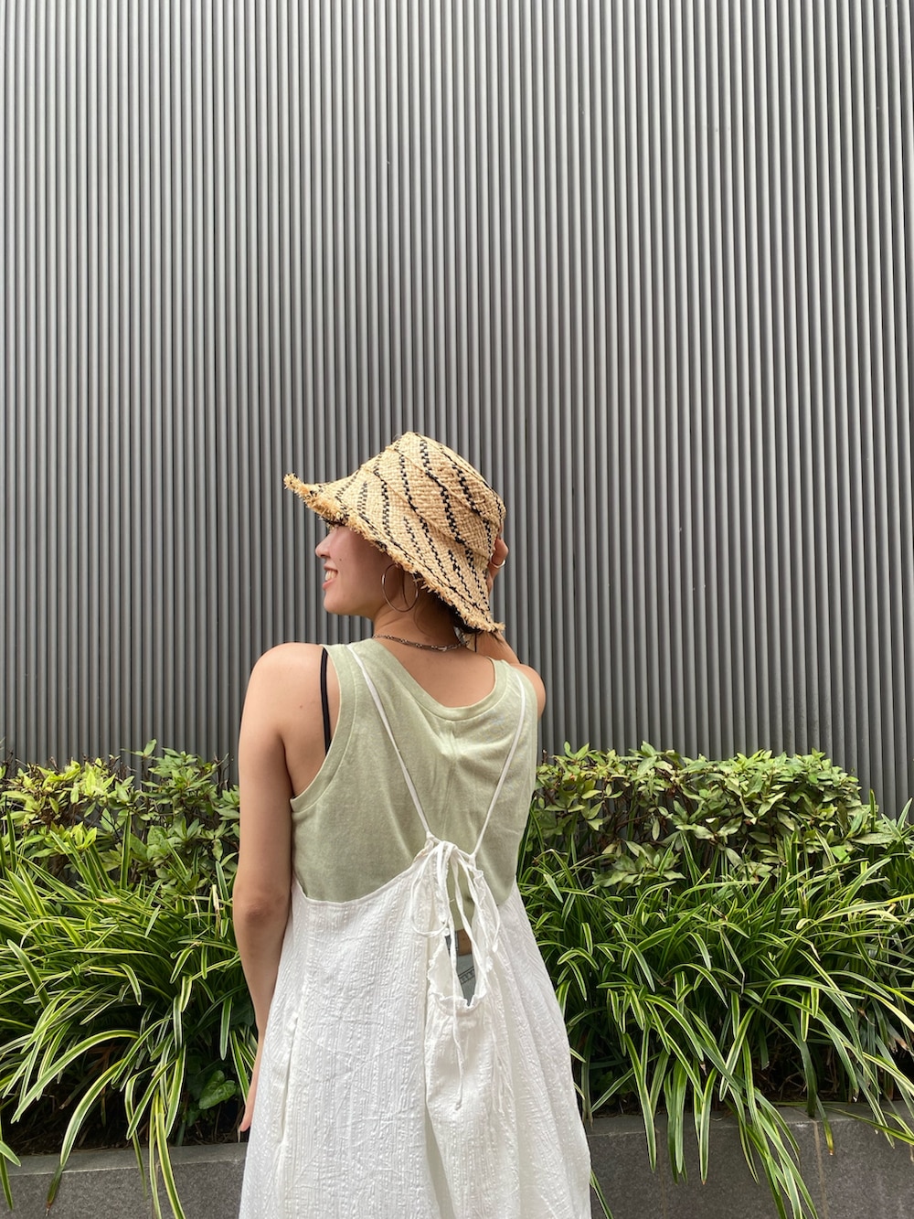 ホワイト系のワンピース、グリーン系のタンクトップ、ブルー系のデニムパンツを着用したレディースの夏コーディネートの4枚目の写真