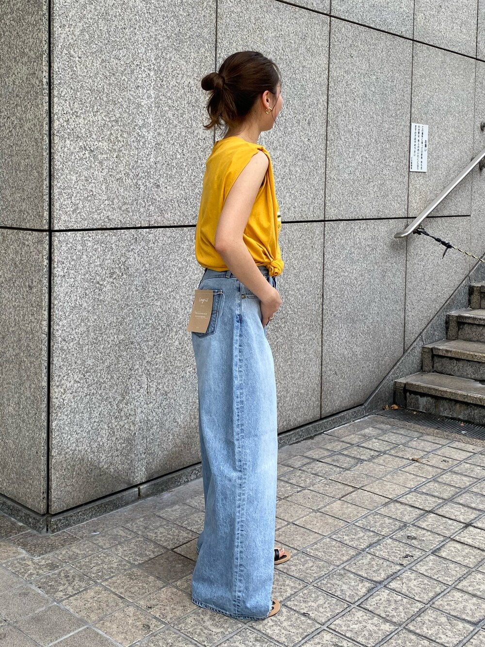 ブルー系のデニムパンツ、イエロー系のTシャツ/カットソー、ブラック系のサンダルを着用したレディースの夏コーディネートの2枚目の写真