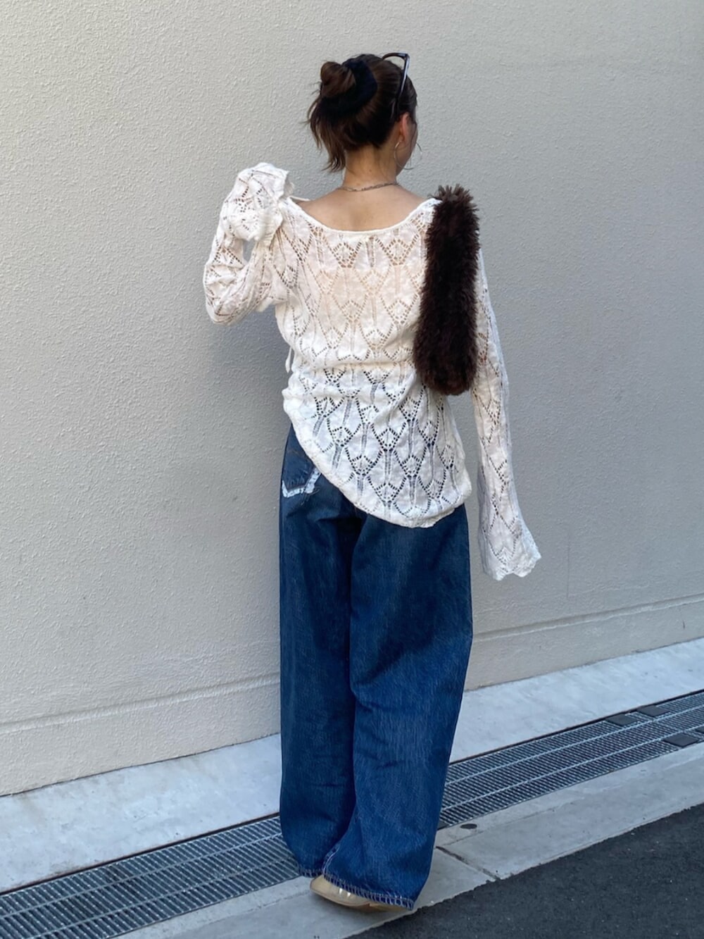 ブルー系のデニムパンツ、ホワイト系のニット/セーター、ブラウン系のハンドバッグを着用したレディースの夏コーディネートの3枚目の写真